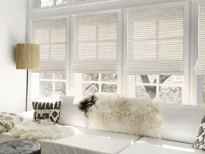 The image shows a well-lit, modern interior space with a large white sectional sofa adorned with a fluffy fur throw.