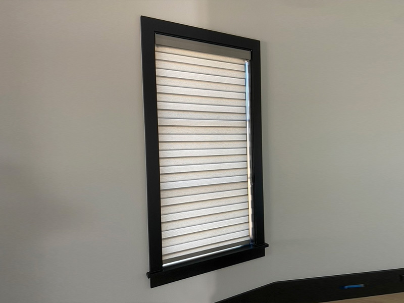 An image of a window with horizontal blinds partially closed, set against a plain wall.